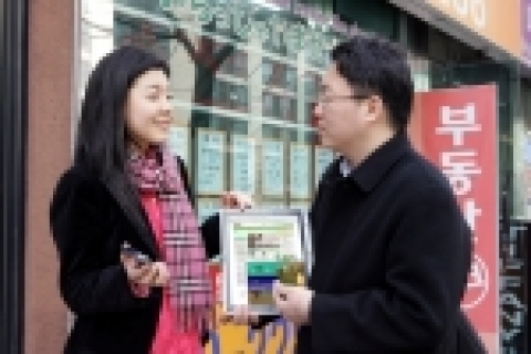 데이콤 비지트 이용고객이 아파트 시세 및 투자전략을 담은 동영상을 보며 주변 부동산중개업소에 붙은 시세표와 비교하고 있다. 
