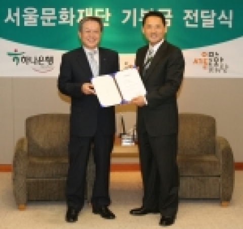 김종열 하나은행장이 유인촌서울문화재단 대표에게 기부금 1억원 증서를 전달하는 모습임.