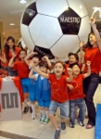 한국 대표팀 응원의 상징인 레드 티셔츠를 입은 마에스트로 첫번째 고객 가족과 어린이들이 대형 축구공 앞에서 파이팅을 외치고 있다.