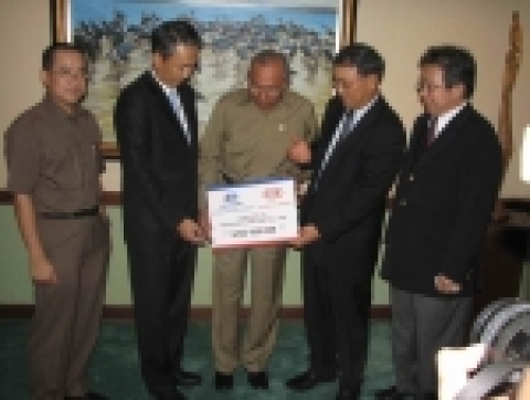 Indonesian Minister for Social Affairs Bachtiar Chamsyah (center) accepts a US$100,000 donation from