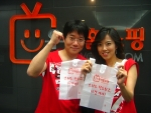 클린 월드컵 캠페인을 전개하는 우리홈쇼핑의 김건우 쇼호스트(왼쪽)와 김미정 쇼호스트(오른쪽)가 '스위스 청소하고, 16강 가자!'라는 문구가 새겨진 쓰레기 봉투를