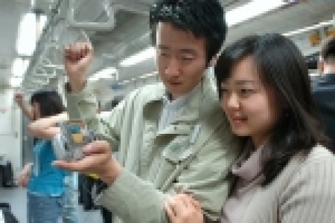지하철에서 tu방송을 보고 있는 남녀 모습