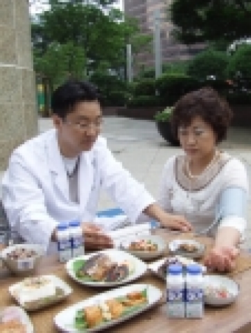 의료진이 한 중년여성의 혈압을 체크하고, 그에 맞는 식단을 보여주고 있다