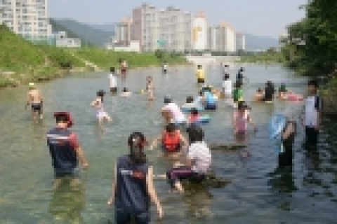 경남은행 봉사단이 희망이 자라는 열린학교에서 봉사 도우미로 아이들과 물놀이를 하고 있다.