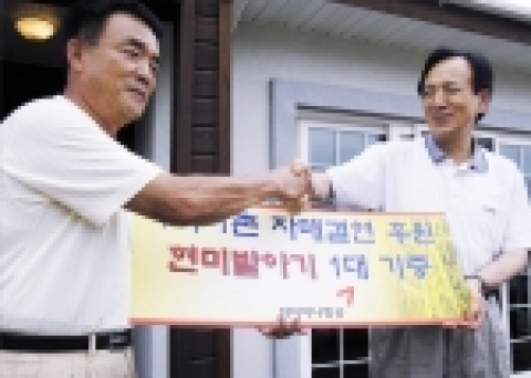 아시아나항공 강주안사장(우측)이 첫 농촌봉사활동을 기념하며 현미발아기 증정서를 외삼포2리 신성교 이장에게 전달하고 있다.