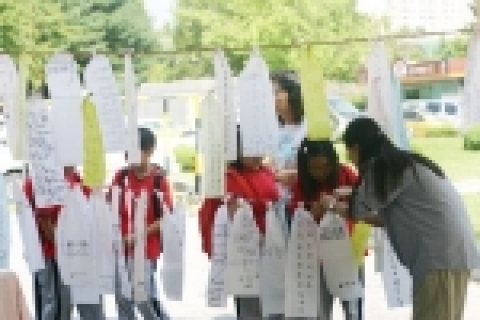 한국건강연대 활동가의 도움을 받아 기원문을 묶고 있는 어린이