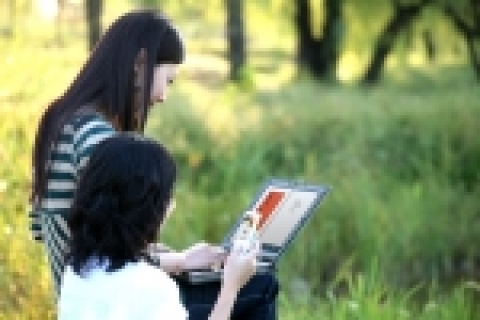 가을을 맞은 20대 여성들이 공원 벤치에 앉아 노트북과 휴대폰으로 전자책을 읽고 있다.