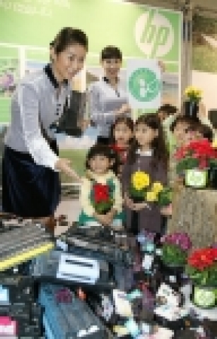 다쓴 프린트 카트리지를 재활용한 플라스틱으로 만든 꽃 화분을 선물로 받은 아이들이 한국HP의 환경프로그램에 대한 설명을 듣고 있다. 이날 친환경상품진흥원으로 부터 친환경인증마크를 