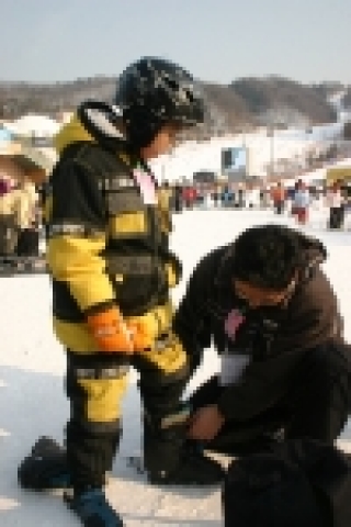 한미은행노조 진창근 홍보국장이 아동에게 스키화를 신겨주고있다.
