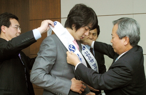신상훈 은행장이 송일국씨에게 명예홍보대사 어깨띠를 둘러주는 모습