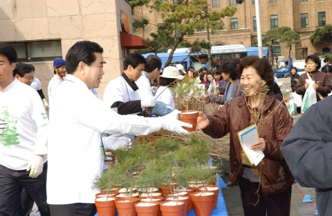 62주년 식목일을 앞두고 30일 서울 동숭동 마로니에 공원에서 개최한 ‘내 나무 갖기 캠페인’중 시민들에게 나무묘목을 나누어 주고 있는 서승진 산림청장( 사진 좌 )