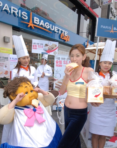 파리바게뜨 홍대역점 행사장에서 거대한 뚱뚱녀가 ‘나를 위한 선택 슬림 53.5’를 먹고 날씬해진 날씬녀를 쳐다보며 부러워하고 있다.