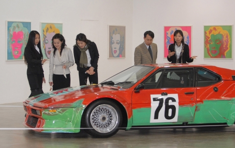 팝 아트의 거장 앤디워홀이 그린 BMW 아트카와 그의 대표작인 마릴린먼로 시리즈 작품에 매료된 관람객들의 모습.