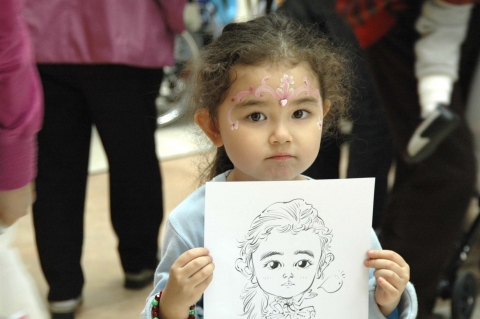 어린이가 축제마당에 참여하여 캐리커쳐한 그림을 들고 기뻐하고 있다.