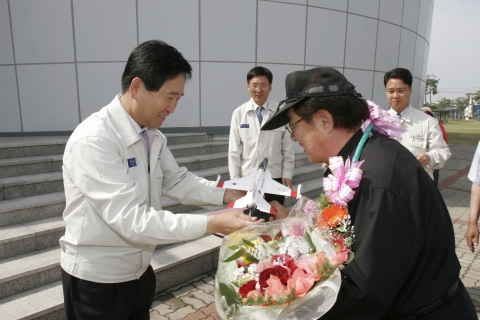 KAI 하성용전무가 200만번째 관람객인 김덕일씨에게 축하 꽃다발, T-50모형 평생회원증을 전달하면서 축하하고 있다.