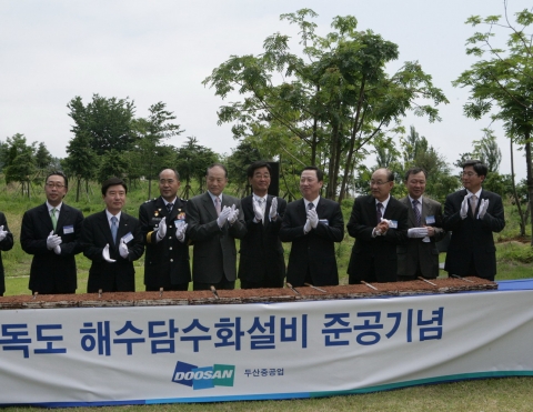 두산중공업이 기증한 독도 해수 담수화 설비 준공행사를 축하하기 위해 관계자들이 대형 시루떡을 자르고 있다. (왼쪽부터 박지원 두산중공업 부사장, 이남두 두산중공업 사장, 송강호 경