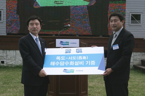 두산중공업 이남두 사장(왼쪽)이 최이환 독도관리사무소장에게 해수 담수화 설비를 기증하고 있다. 