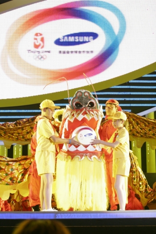 삼성Anycall희망소학교 어린이들도 이번 행사에 초청되었다. 희망소학교 어린이가 용에게 삼성의 소비스(Samsung Olympic Visual Identity System)로 디