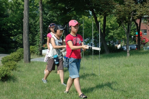 섬머 전파 캠프에 참석한 어린이가 수신되는 신호에 신경을 곤두세워가며 발신기에서 발신되는 전파의 방향을 찾기 위해 이동하고 있다.(대전전파관리소)