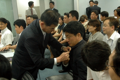 현대정보기술 임원이 베트남 프로젝트 수행직원의 가슴에 태극기를 달아주고 있다.