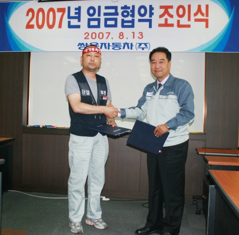 쌍용자동차 최형탁 사장(오른쪽)과 정일권 노조위원장(왼쪽)이 2007년 임금협약 합의서에 서명하고 난 후 서로 악수를 하고있다.