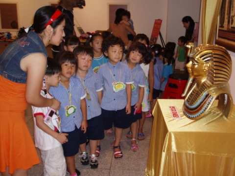 어린이들이 투탄카문왕의 황금가면에 대한 설명을 듣고있다