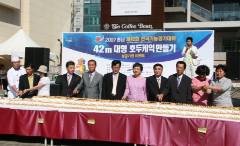 충남 천안 야우리광장에서 펼쳐진 제42회전국기능경기대회 성공기원 이벤트인 42m 호두케익만들기 행사에서 충청남도 기능경기위원회 한상원 운영위원장, 홍보대사인 임대호씨 등 참가자들이 커팅식을 하고 있다