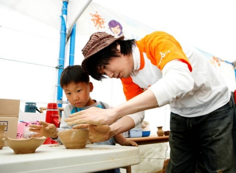 싸이월드 사이좋은세상 일촌봉사대장 김장훈이 아이들과 함께 진지하게 도자기 빚기에 열중인 모습