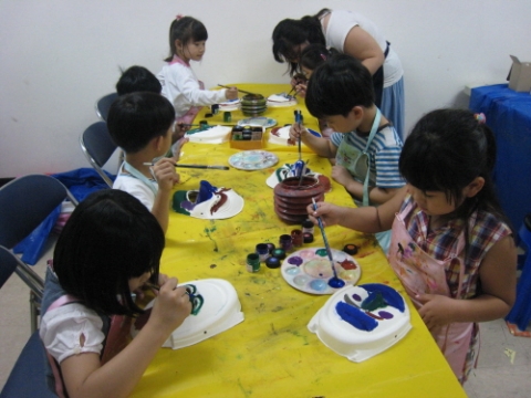 어린이들이 하얀 가면에 색칠을 하고 있다