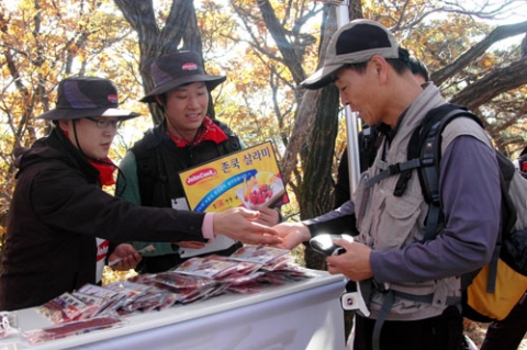 에쓰푸드는 27일 청계산 매봉정상에서 산림 보호 캠페인과 함께  등산객들에게 영양간식으로 좋은 살라미스낵과 비프스틱을  나줘주고 있다.