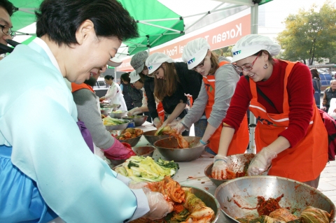 인사동 거리를 관광하던 외국인들이 KTF 김치 알리미 활동에 참석하여 직접 김치를 담그고 맛을 보며 즐거워하는 모습