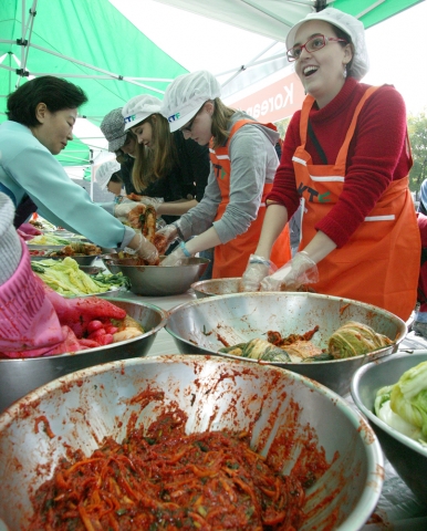 인사동 거리를 관광하던 외국인들이 KTF 김치 알리미 활동에 참석하여 직접 김치를 담그고 맛을 보며 즐거워하는 모습
