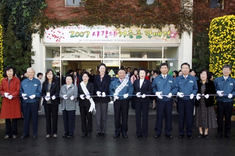 현대중공업 기증품 판매전 개장식. 사진 왼쪽 2번째 현대중공업 민계식 부회장, 왼쪽 6번째 정몽준 국회의원 부인 김영명 여사, 오른쪽에서 4번째 현대중공업 최길선 사장, 오른쪽 3번째 현대미포조선 송재병 사장. 그외 지역 인사 및 현대중공업 임직원들이 개막테이프를 자르고 있다.