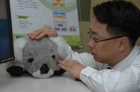 ETRI가 개발에 성공한 감성로봇 '코비'를 연구진이 쓰다듬고 있다.