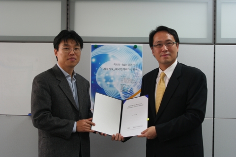 SK 커뮤니케이션즈 검색포털 사업본부 권승환 상무(사진 왼쪽)와 대법원 정보화심의관 백강진 판사 (사진오른쪽)가 콘텐츠 정보 공동 활용을 위한 협정서를 들고 포즈를 취하고 있다.