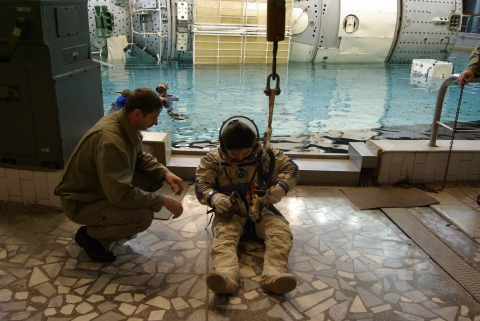 우주복의 고리에 크레인의 고리를 거는 과정