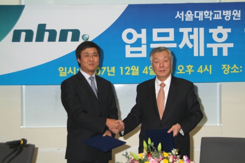 NHN 최휘영 사장(좌)과 서울대병원 성상철 원장이 조인서에 서명 후 악수를 나누고 있다.