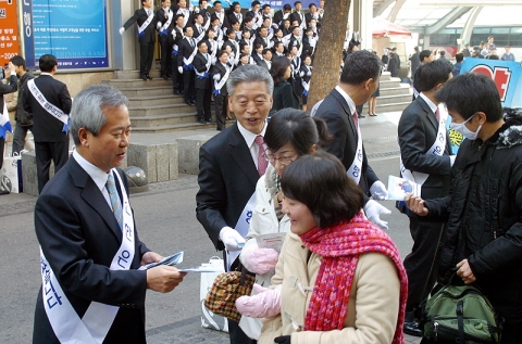신상훈 은행장(왼쪽에서 첫번째)이 임직원들과 지나가는 고객들에게 사은품을 나눠드리며 인사하는 모습