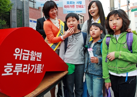 중외제약 임직원들이 서울 영등포구에 있는 한 초등학교 앞에서 16일 호신용 호루라기를 나눠주면서 귀가길 안전수칙에 대해 설명하고 있다.