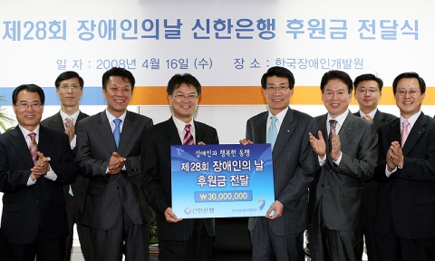 제28회 장애인의 날 후원금 전달식 후 기념 촬영 하는 모습. (좌) 한국장애인개발원 안이문 기획홍보팀장 - 신한은행 임동현 부지점장 -  한국장애인개발원 김규철 총무재무팀장 -  한국장애인개발원 김정열 사무총장 - 신한은행 박찬 부행장 - 신한은행 마경환 부장 - 신한은행 전영철 부부장 -신한은행 조경우 지점장.