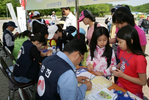 과천 어린이대공원에서 한전사회봉사단과 실종아동전문기관이 함께 이름표를 만들어 달아주고 있는 장면