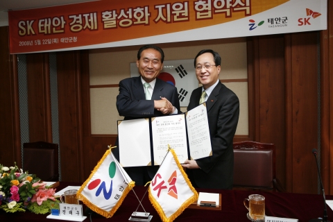 김신배 SK텔레콤 사장(오른쪽}이 22일 충남 태안군청에서 진태구 태안군수와 'SK 태안 경제활성화 지원 협약식'을 체결한 뒤 악수하고 있다.