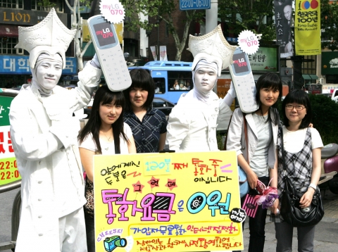 LG데이콤은 지난 25일 대학로와 신촌 등 대학가에서 인터넷 집전화 myLG070을 주제로 한 마임 퍼포먼스를 펼쳤다. myLG070폰을 든 퍼포머들이‘120분 째 통화중, 통화요금은 무료’라는 내용의 안내판을 사이에 두고 행인들과 기념 촬영을 하고 있다.