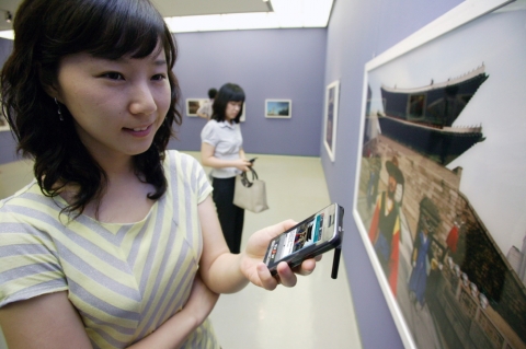 서초동 예술의 전당 한가람미술관에서 열리고 있는  ‘매그넘 코리아’ 사진전에서 KTF 도우미가 휴대폰에서 보았던 동일한 사진을 감상하고 있다