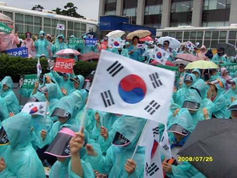 7월 25일 보건복지부 앞마당에서 시민들이 폭우 속에서 황우석 박사의 국내연구 승인을 보건복지부에 촉구하고 있다. 