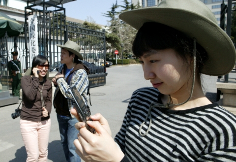 KTF 도우미가 중국 베이징에서 쇼 자동로밍을 이용해 음성통화를 하고 문자메시지를 보내고 있다