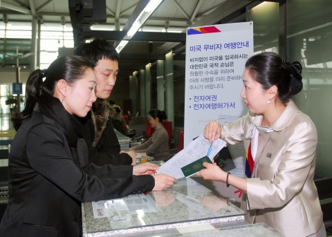 아시아나항공의 공항 직원이 손님들에게 미국비자면제프로그램에 대해 안내하고 있다