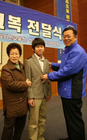 삼성전자 LCD사업부 나눔경영그룹 배성우부장이 한 학생에게 교복을 입혀주고 있다.