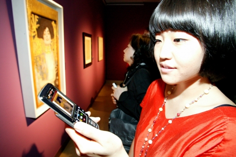 서초동 예술의 전당 한가람 미술관에서 열리고 있는 ‘구스타프 클림트展’에서 KTF 도우미가 휴대폰에서 서비스되고 있는 작품과 동일한 작품을 감상하고 있다