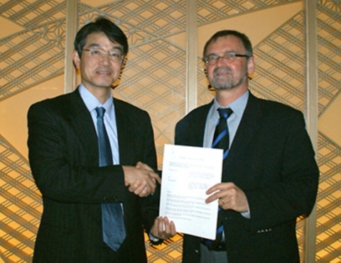 소니(Sony Corporation)의 디지털 이미징 사업 부문의 시게키 이시즈카(Shigeki Ishizuka) 사장(왼쪽)과 칼 자이스(Carl Zeiss AG) 카메라 렌즈 사업부의 윈프리드 슐러(Winfried Scherle) 부사장이 계약 연장을 축하하며 악수를 나누고 있다.